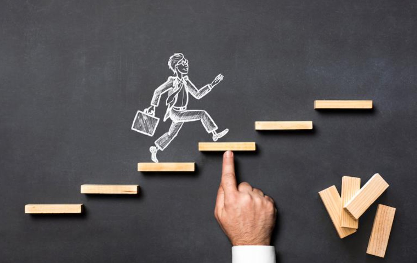 Silhouette of a person climbing stairs toward a glowing arrow, symbolizing career growth
